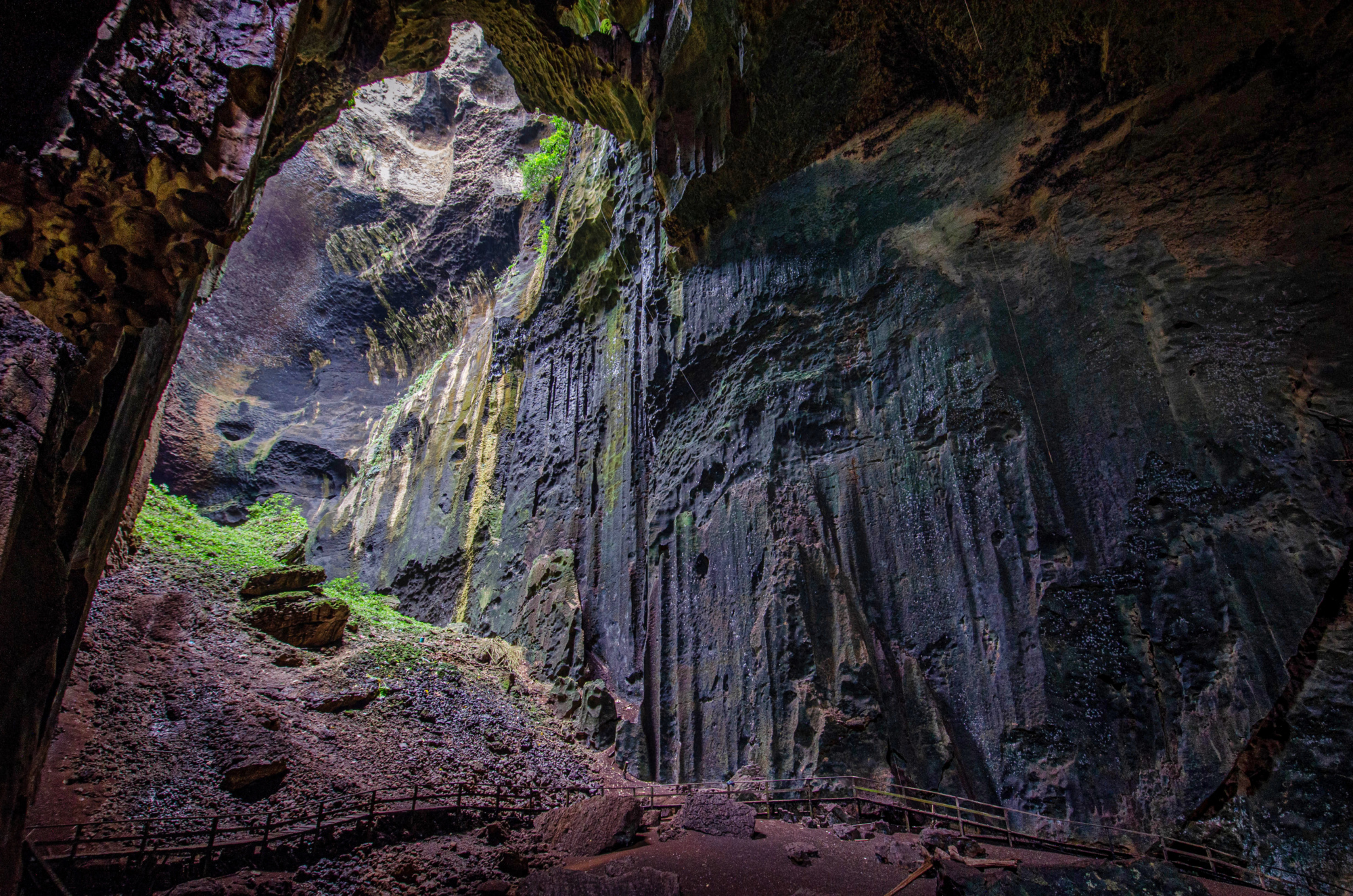 Simud Hitam cave mouth from inside, light shaft, boardwalk in silhouette